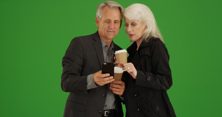 Modern senior couple using smartphone to get directions on green screen