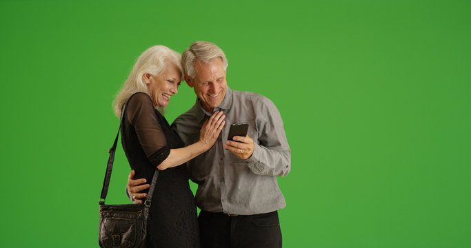 Happy Senior Couple Out On Date Using Smartphone Together On Green Screen