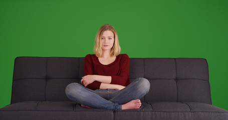 Obraz premium Pretty young woman relaxing on the sofa looking at camera on green screen