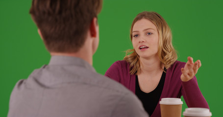 Female professional having conversation with male coworker on green screen