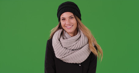 Portrait of attractive woman in winter clothes smiling at camera on green screen