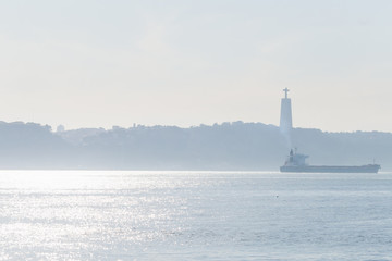 The river Tagus is a large navigable river. a large cargo ship and a silhouette of the opposite...
