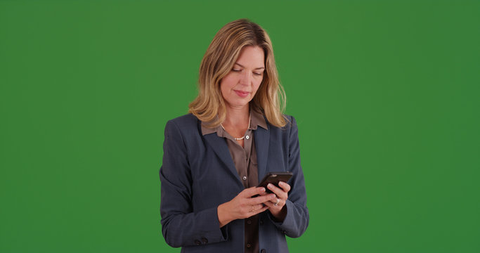 Professional businesswoman texting on smartphone on green screen