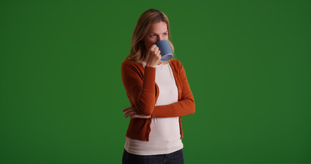 Middle aged Caucasian woman drinking from coffee mug on green screen