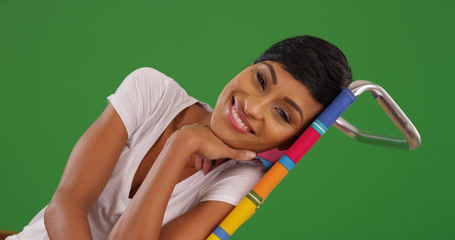 Young black woman smiling at camera reclining on beach chair on green screen