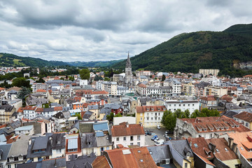 Fototapeta premium Roofs of buildings and The Church of the Sacred Heart in Lourdes, France.