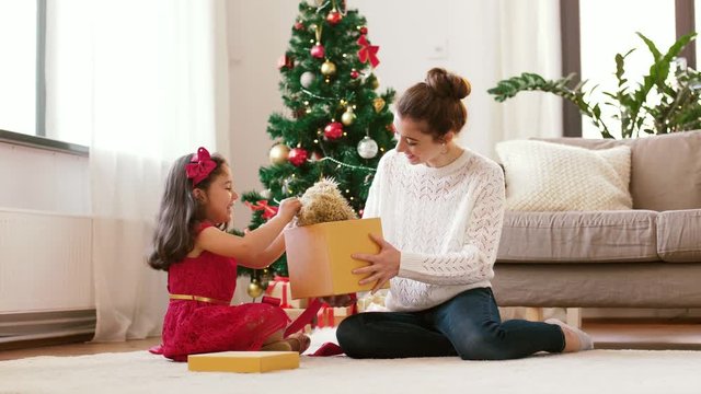 holidays, family and celebration concept - happy mother giving daughter christmas gift at home