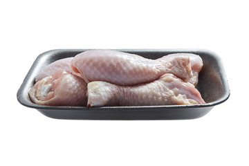 Raw and uncooked chicken legs with skin in a grey plastic container. Fresh meat of poultry in tray, isolated on white background