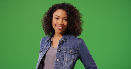Portrait of happy black woman in jean jacket posing on green screen