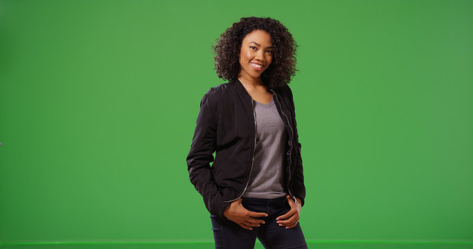 Beautiful black millennial girl posing for camera smiling on green screen