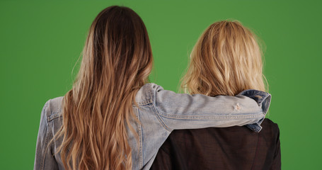 Rear view of female best friends holding each other on green screen