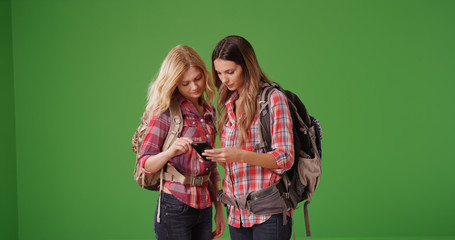 Two female backpackers using phone to get directions on green screen