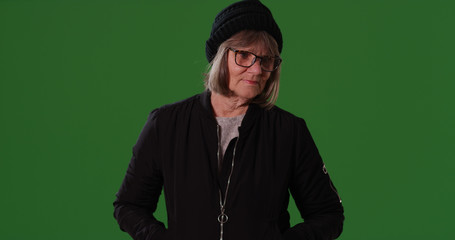 Pensive old white lady in autumn clothes standing alone on green screen