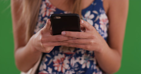 Close up of young woman's hands messaging with cellphone on greenscreen