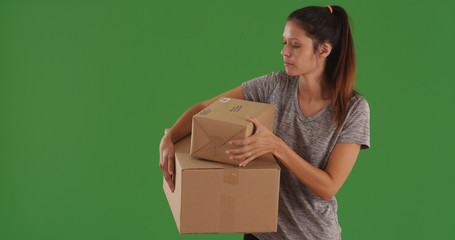 Casual young woman standing carrying shipping boxes on green screen