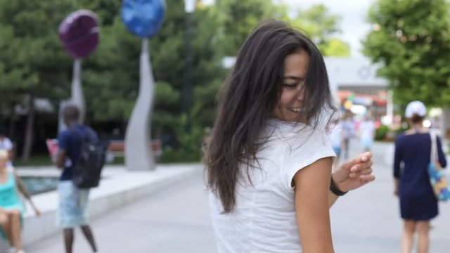 Back view of seductive hot brunette woman walking in park, turning and smiling straight to camera, follow me concept. Happy moment, romantic atmosphere. Female portrait