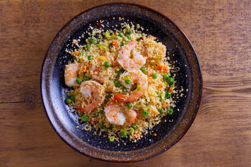 Shrimps with couscous, green peas, leeks and carrot. View from above, top studio shot