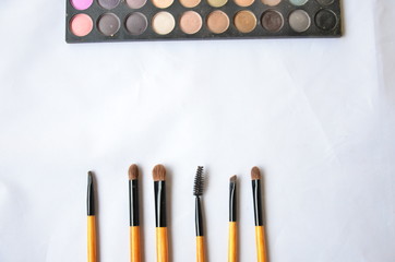 Cosmetic set of brushes and eye shadow on white background