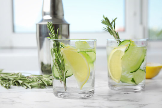 Refreshing lemon cocktail with rosemary on marble table