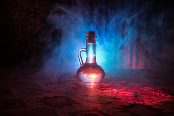 Antique and vintage glass bottles on dark foggy background with light. Poison or magic liquid...