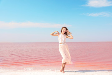 Fototapeta na wymiar Beautiful woman posing near pink lake on sunny day