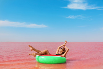 Fototapeta na wymiar Beautiful woman on inflatable ring in pink lake