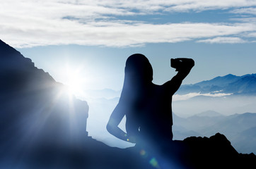 Woman taking selfie in the mountains during sunset