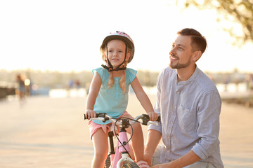 Fototapeta na wymiar Father teaching daughter to ride bicycle on street