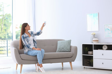 Young woman with air conditioner remote at home