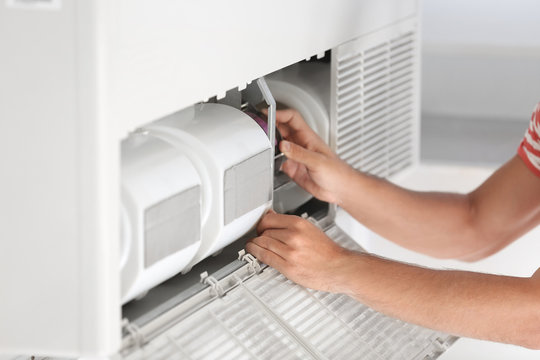 Young man fixing air conditioner at home, closeup