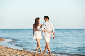 Happy young couple walking together on beach