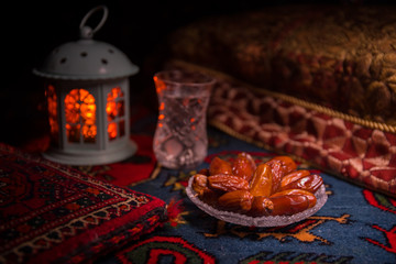 Water and dates. Iftar is the evening meal. View of decoration Ramadan Kareem holiday on carpet. Festive greeting card, invitation for Muslim holy month Ramadan Kareem. Dark background