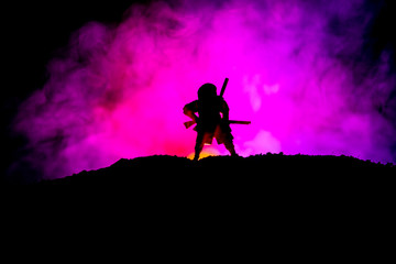 Naklejka na ściany i meble Fighter with a sword silhouette a sky ninja. Samurai on top of mountain with dark toned foggy background.