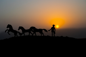 Cowboy concept. Silhouette of Cowboys at sunset time. A cowboy silhouette on a mountain with an yellow sky.
