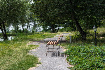 Empty bench at park near pond by sunny day, bench at the lake in the forest. Azerbaijan Nature.