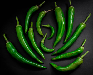 Hot green pepper on black background. top view
