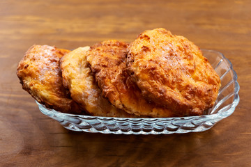 Home baking-round cookies stuffed with cottage cheese in a glass plate on a wooden background.