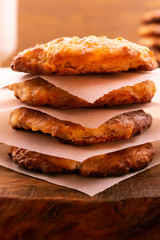 Four cookies with a ruddy crust, stacked on top of each other on a wooden background, vertical frame, close-up.