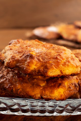 Round biscuits with a ruddy crust, stacked in a glass plate, close-up, vertical frame.