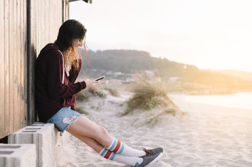 Young Girl with smartphone outdoors next to the wooden house