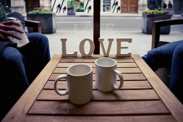 Couple relaxing with a coffee and word LOVE on wood.
