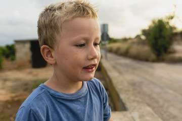 Blond boy making funny faces outdoors