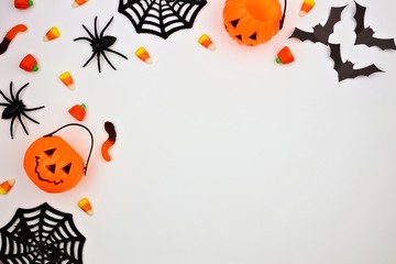 Halloween corner border of scattered candy and decor. Flat lay over a white background. Copy space.