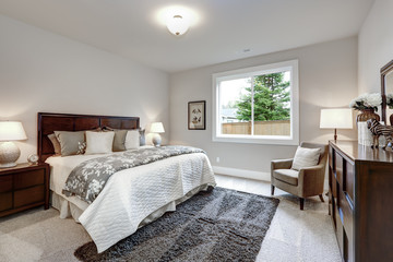 Light modern master bedroom interior with darkwood bed and dresser