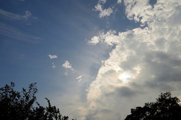 大きな雲に隠れた太陽の光で照らされる細い筋雲