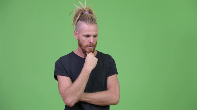 Serious bearded man with dreadlocks thinking while looking down