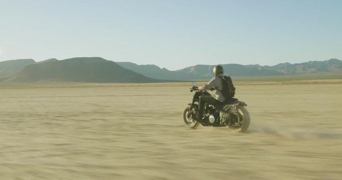 Riding motorcycle through dry lake bed.