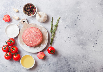 Raw minced homemade grill beef burger with spices and herbs. Top view and space for text.On top of chopping board and kitchen table background. With pepper salt and garlic.