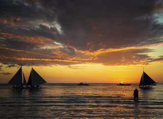 sunset with sailing boats and tourists in boracay island philippines