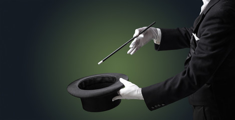 Illusionist white hand wants to conjure with magic wand from a black cylinder something